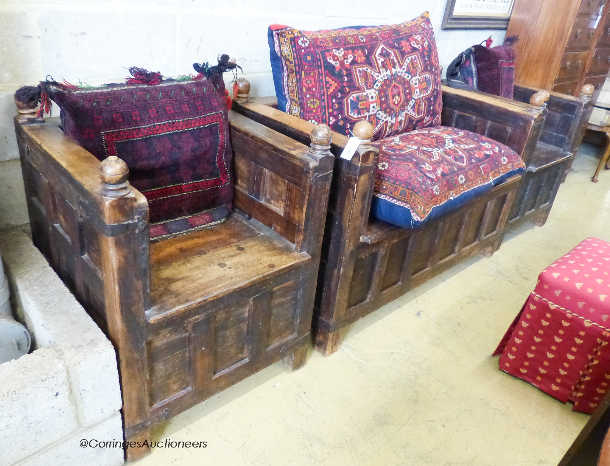 An Indian iron mounted, paneled hardwood hinged box seat bench and two chairs, all with Caucasian/Turkish cushions. Bench - W-138cm, D-69, H-91cm.